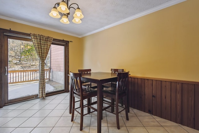 dining area with light tile patterned floors, a wainscoted wall, crown molding, a textured ceiling, and a chandelier