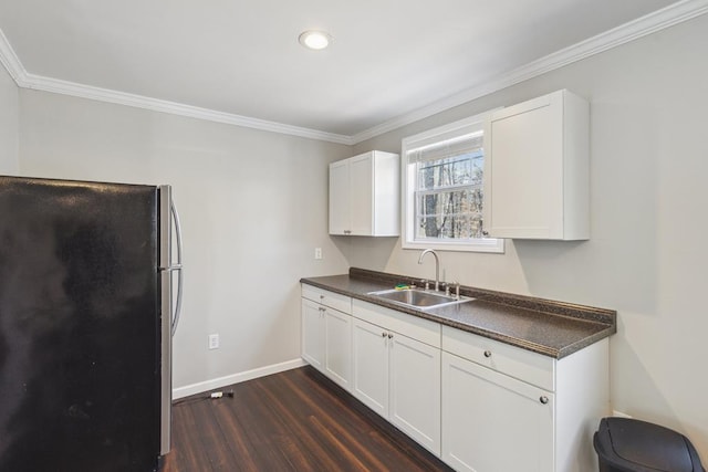 kitchen with dark countertops, dark wood-style flooring, a sink, and freestanding refrigerator