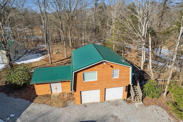 view of front of house featuring a garage, stairway, metal roof, and gravel driveway