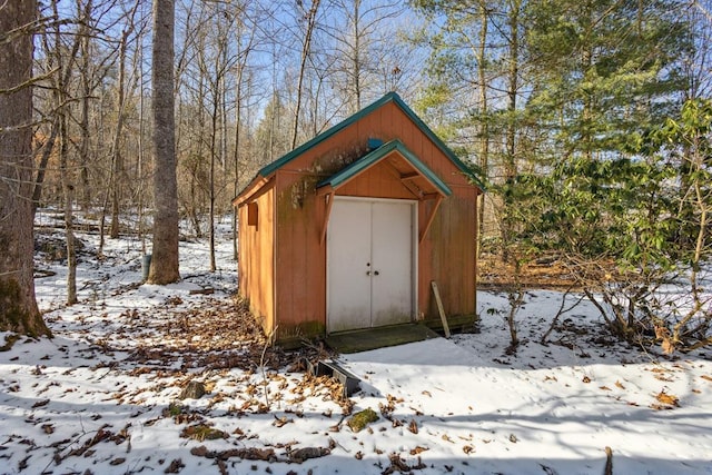 snow covered structure with an outdoor structure and a storage shed