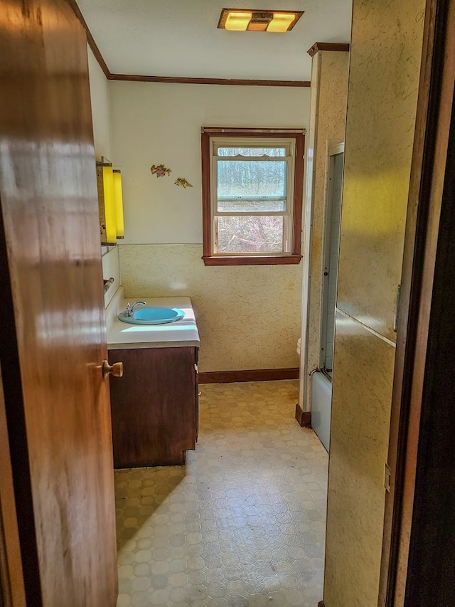 bathroom with crown molding, vanity, shower / bath combination with glass door, baseboards, and tile patterned floors