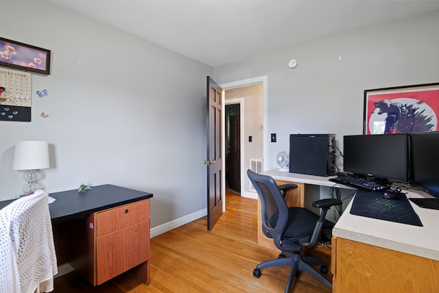 office area featuring light wood finished floors, visible vents, and baseboards