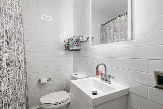 bathroom with tile walls, decorative backsplash, a shower with shower curtain, toilet, and vanity