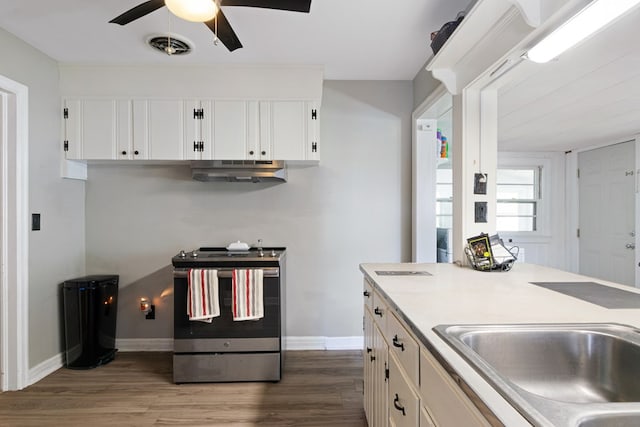 kitchen with white cabinets, dark wood-type flooring, stainless steel electric stove, under cabinet range hood, and a sink