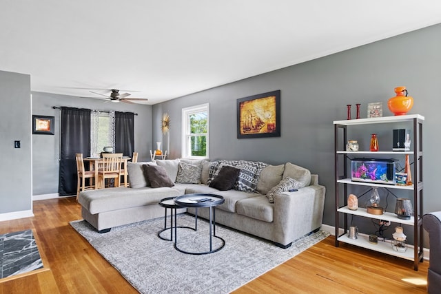 living room with ceiling fan, baseboards, and wood finished floors