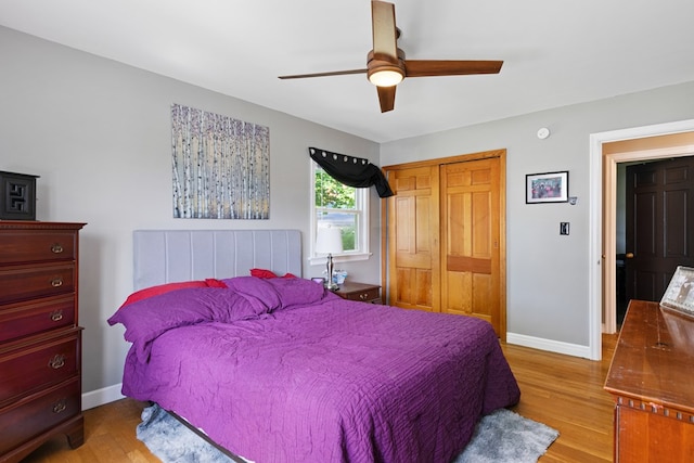 bedroom featuring baseboards, a closet, a ceiling fan, and light wood-style floors