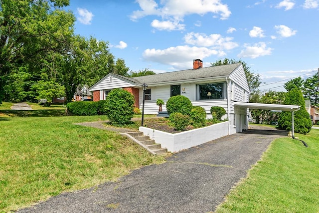 ranch-style home with a carport, aphalt driveway, a chimney, and a front yard