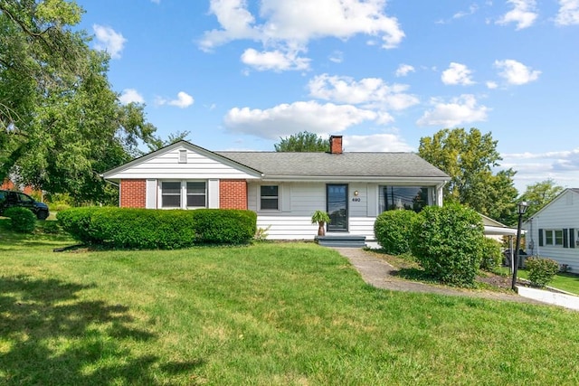 ranch-style house with brick siding, a chimney, and a front lawn