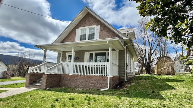 view of front of home with a front yard, an outbuilding, a porch, and a storage shed