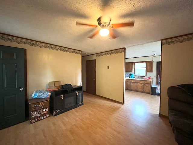 interior space featuring ceiling fan, crown molding, a textured ceiling, and light hardwood / wood-style flooring