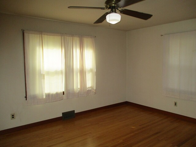 unfurnished room featuring a ceiling fan, visible vents, baseboards, and wood finished floors
