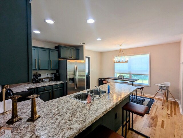 1251 Epperly Mill Rd, Floyd, VA 24091 - kitchen featuring stainless steel refrigerator with ice dispenser, light stone countertops, light wood finished floors, a breakfast bar area, and recessed lighting