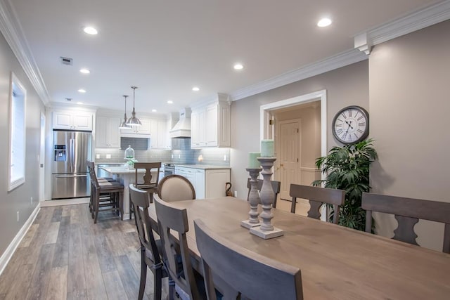 dining room featuring light wood-type flooring, visible vents, crown molding, and recessed lighting