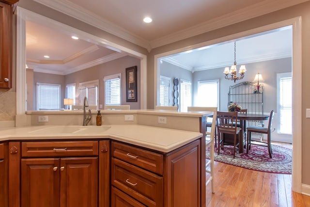 kitchen with light wood-style floors, brown cabinetry, a sink, and light countertops