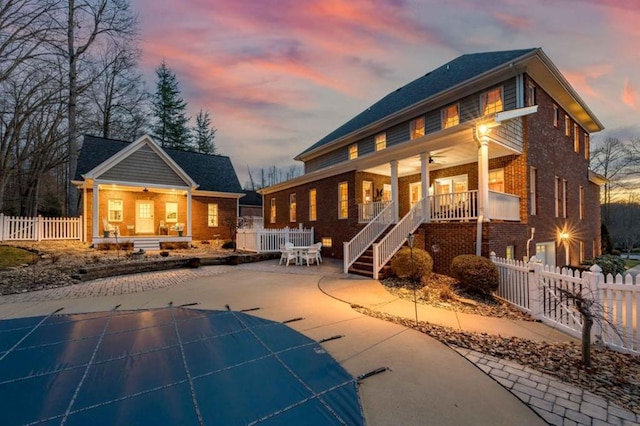 rear view of property featuring fence private yard, a porch, a ceiling fan, and brick siding