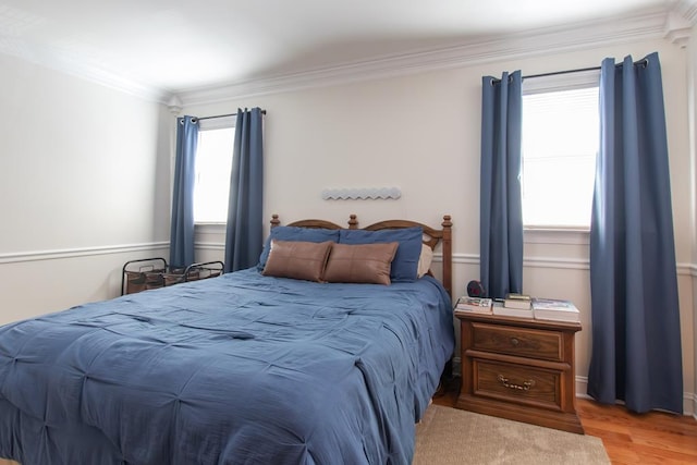 bedroom featuring multiple windows, crown molding, and light wood finished floors