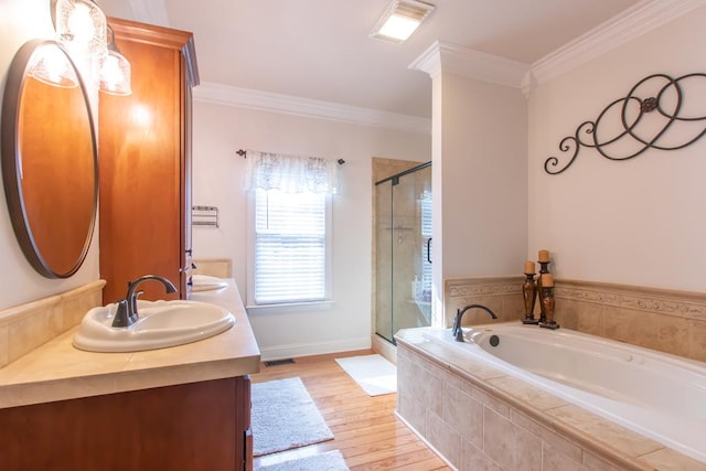 bathroom featuring double vanity, ornamental molding, a sink, a shower stall, and wood finished floors