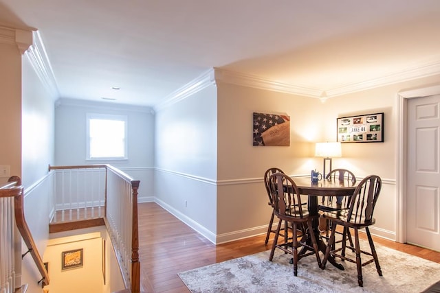 dining room with crown molding, baseboards, and wood finished floors