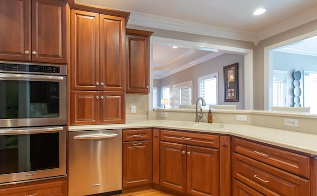 kitchen with stainless steel appliances, tasteful backsplash, light countertops, ornamental molding, and a sink