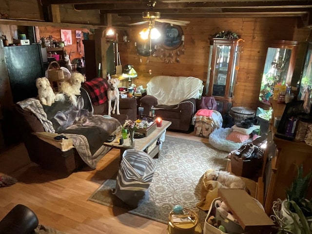 living room with wooden walls, a ceiling fan, and wood finished floors