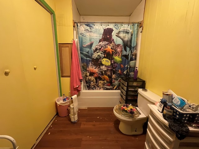 full bath featuring toilet, wood finished floors, and shower / bath combination with curtain