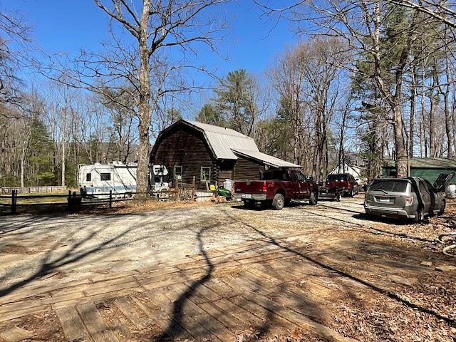 view of side of home with a barn, a gambrel roof, and fence