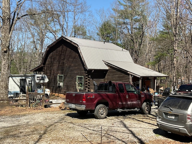view of side of home with a gambrel roof, metal roof, and log exterior