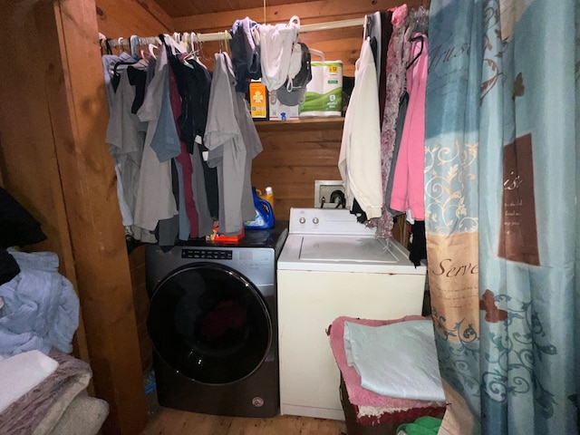 clothes washing area featuring separate washer and dryer, laundry area, and wood finished floors