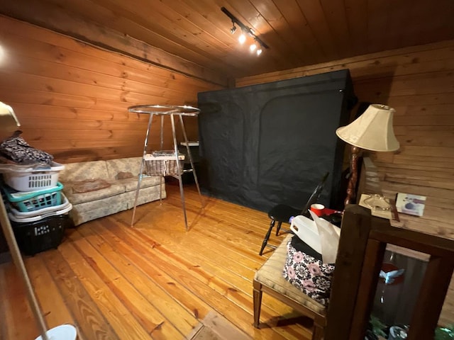 bedroom with wood walls, rail lighting, wood finished floors, and wood ceiling