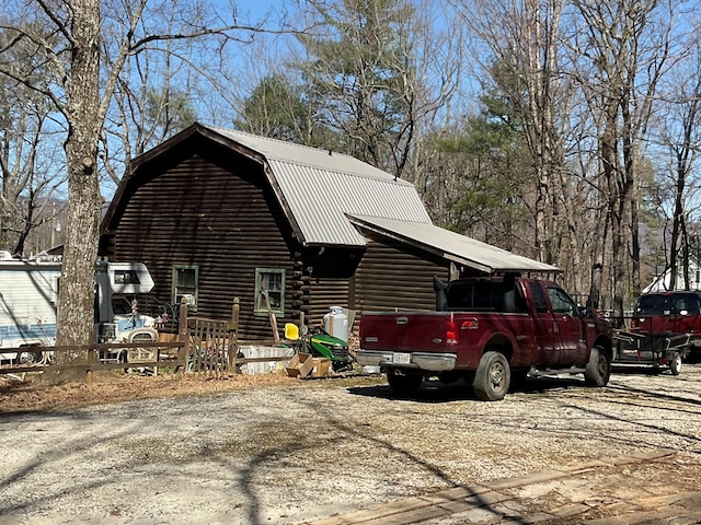 view of side of property featuring log exterior, a gambrel roof, and metal roof