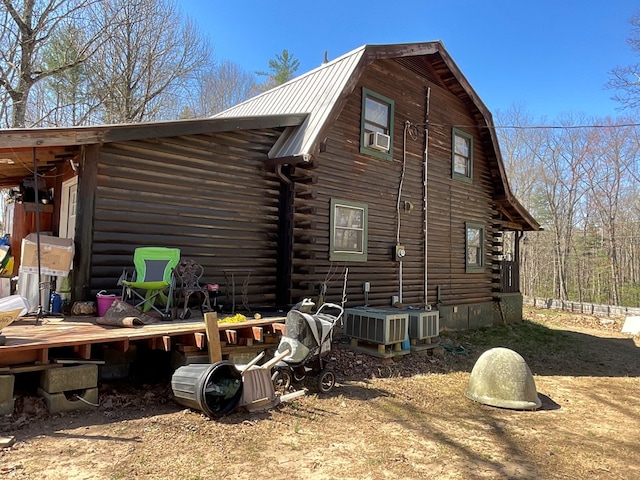 view of side of home with metal roof, cooling unit, central air condition unit, a gambrel roof, and log siding