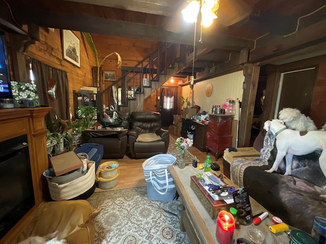 living room featuring wood finished floors, wooden walls, and stairway