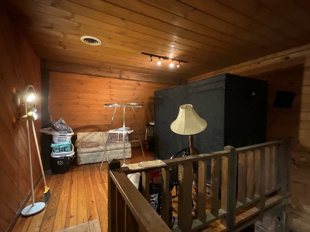 additional living space with wood walls, wood-type flooring, visible vents, and wood ceiling