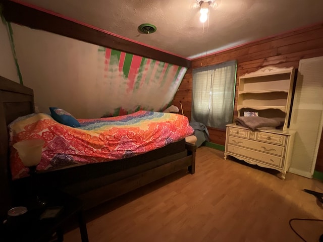 bedroom featuring wood walls, light wood finished floors, and visible vents
