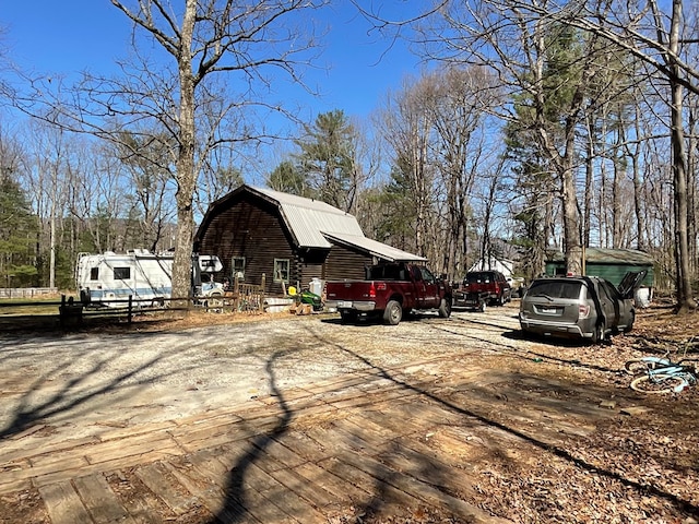 view of side of property featuring a barn, log siding, an outdoor structure, and a gambrel roof