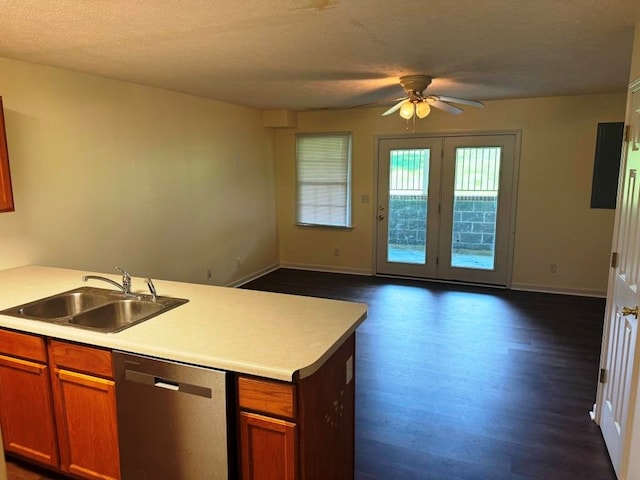 kitchen with brown cabinets, open floor plan, light countertops, stainless steel dishwasher, and a sink