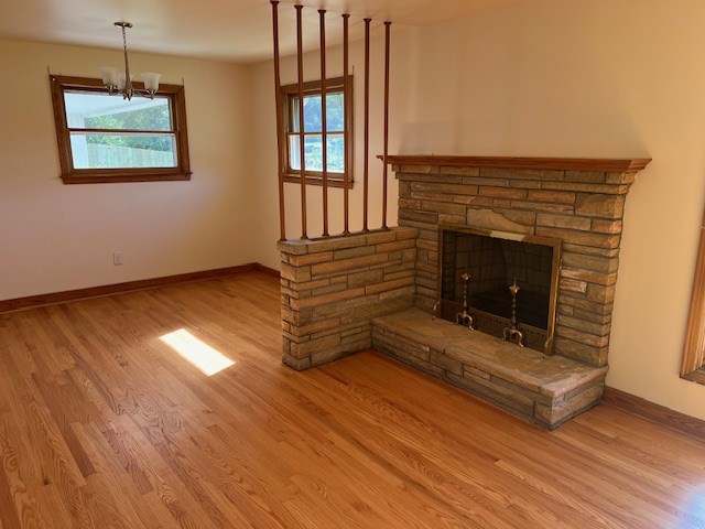 unfurnished living room featuring hardwood / wood-style flooring, an inviting chandelier, and a fireplace