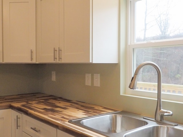 kitchen featuring white cabinets, sink, and wooden counters