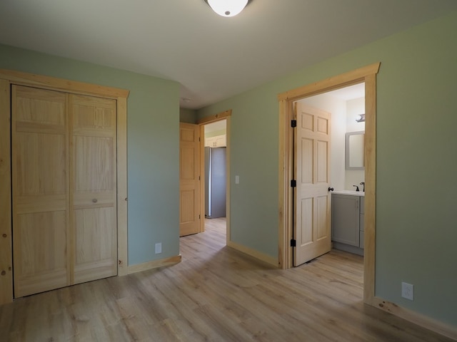 unfurnished bedroom featuring light hardwood / wood-style flooring, stainless steel fridge, and a closet