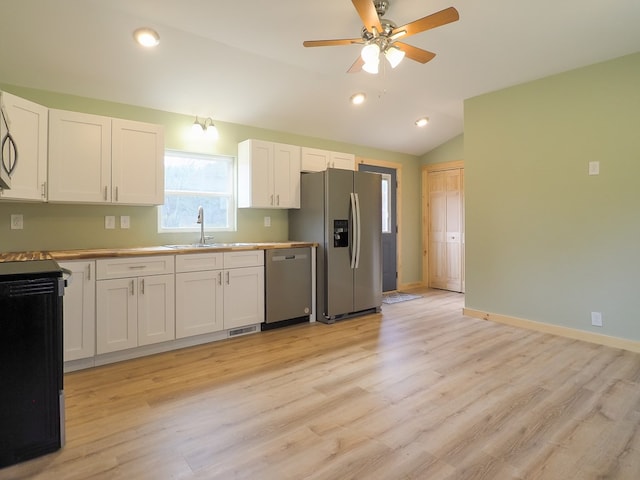 kitchen with lofted ceiling, sink, white cabinetry, stainless steel appliances, and light wood-type flooring