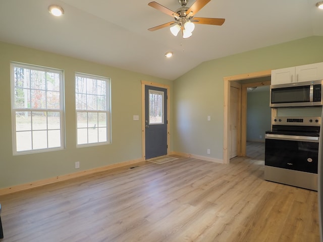 kitchen with lofted ceiling, white cabinetry, appliances with stainless steel finishes, ceiling fan, and light hardwood / wood-style floors