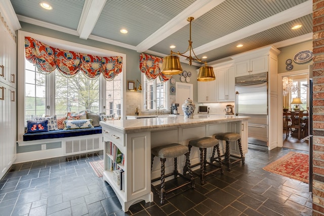 kitchen featuring a center island, crown molding, white cabinets, stainless steel built in refrigerator, and beam ceiling