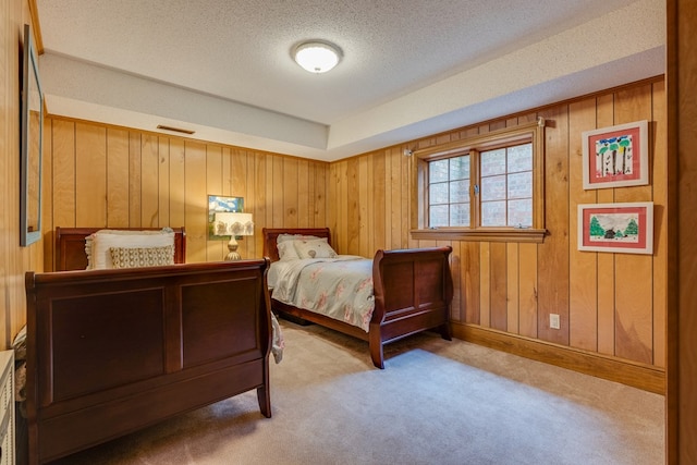 bedroom featuring wooden walls, visible vents, baseboards, a textured ceiling, and carpet flooring