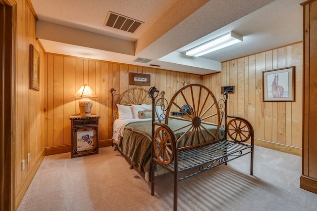 bedroom with light colored carpet, wood walls, visible vents, and baseboards