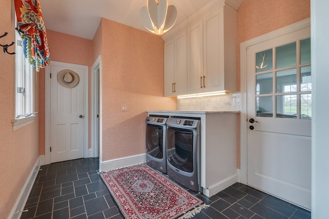 washroom with cabinet space, dark tile patterned floors, a healthy amount of sunlight, and washing machine and clothes dryer