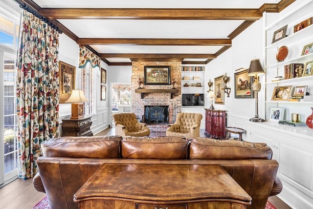 living area featuring a decorative wall, built in features, wood finished floors, and beamed ceiling