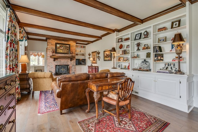 living area with built in features, light wood-style floors, beamed ceiling, and a fireplace