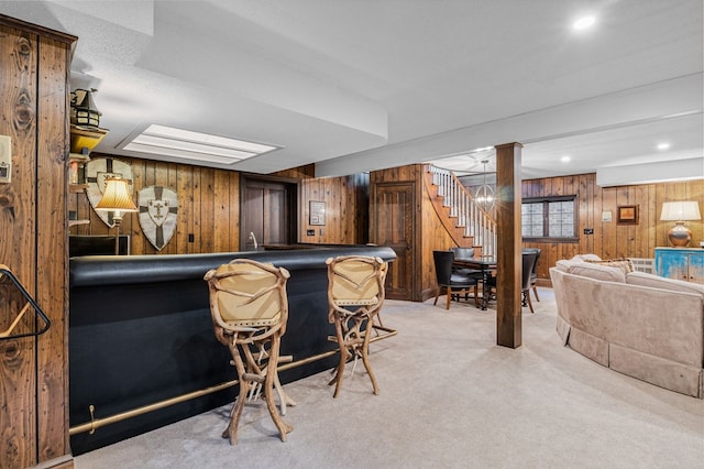 bar featuring wooden walls, light carpet, stairs, and indoor wet bar