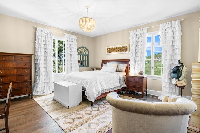 bedroom featuring a chandelier, wood finished floors, and multiple windows