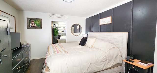 bedroom featuring dark wood-type flooring, a textured ceiling, and ensuite bath